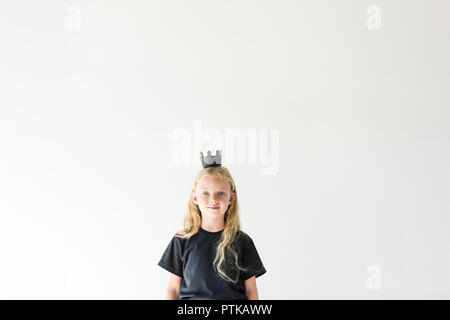 Adorable Kind mit langen Lockigen mit schwarzen Krone hören und lächelnd an der Kamera auf Weiß isoliert Stockfoto