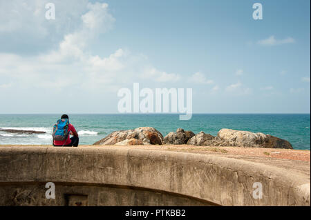 Reisender auf der Wand sitzen, auf das Meer Blick von der Stadtmauer, Festung Galle, Sri Lanka Stockfoto