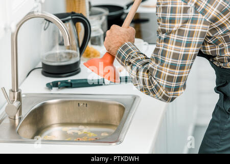 Zugeschnittenes Bild der Klempner mit Kolben und Reinigung Spülbecken in der Küche Stockfoto