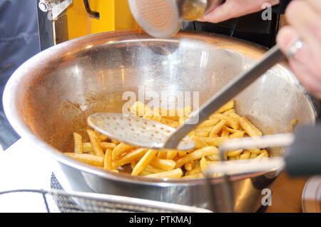 Im Foodtruck von einems Imbiss würzt jemand Pommes Frites/Pommes frites in einer Edelstahl Metallschüssel mit viel Salz und Paprika Gewürz Stockfoto