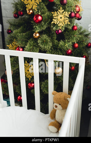 Hohe Betrachtungswinkel und der Teddybär in Kind vor dem Weihnachtsbaum Stockfoto