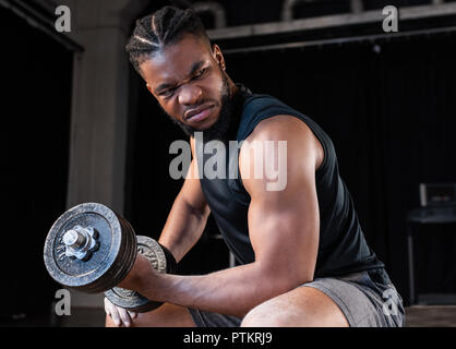 Junge konzentrierte sich afrikanische amerikanische Sportler Training mit Hanteln und Wegsehen in der Turnhalle Stockfoto
