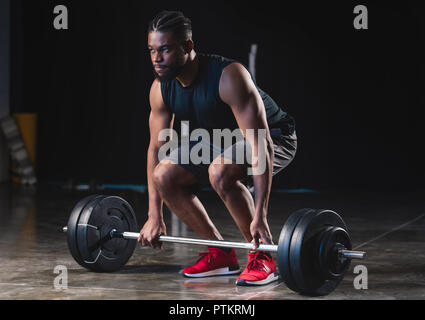 Fokussierte muskulöse afrikanische amerikanische Sportler anheben Barbell und Wegsehen in der Turnhalle Stockfoto