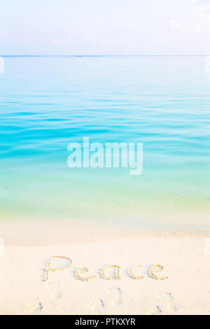 Das Wort Frieden in den Sand an einem Strand mit Morgen Meer Hintergrund Stockfoto