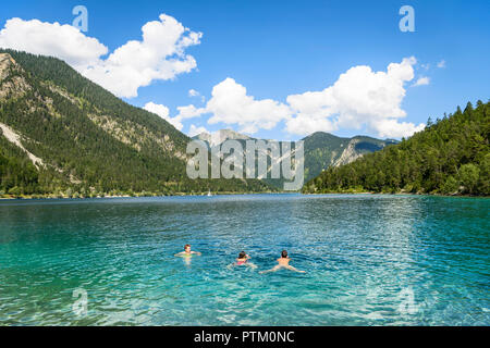 Drei Menschen baden, schwimmen im See Plansee, Ansicht vom Ufer, türkisfarbenes Wasser, See, Berg Landschaft Stockfoto