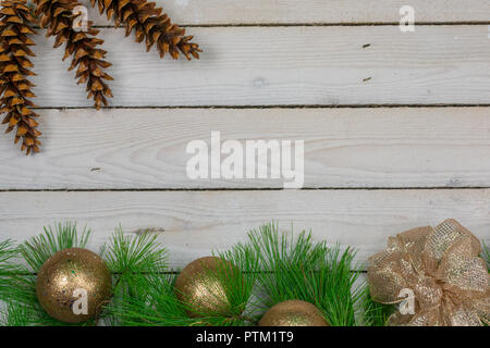 Eine Grenze von white pine Äste, drei Gold Ornamente und einen goldenen Bogen entlang der Unterseite mit drei weißen Tannenzapfen in der linken oberen Ecke Stockfoto