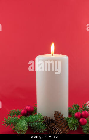 Eine einzige Kerze mit Zweigen Fichte mit roten Beeren Cluster umgeben und Tannenzapfen Stockfoto