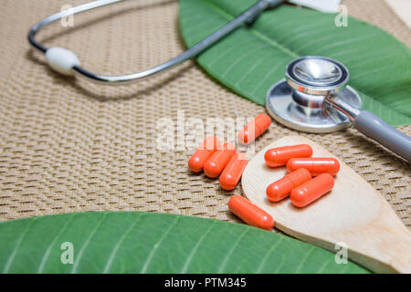 Kräutermedizin in rot Kapseln auf Holzlöffel mit Kopie Raum für medizinische Hintergrund, gesunde Ernährung mit natürlichen Produkt für gutes Leben. Stockfoto