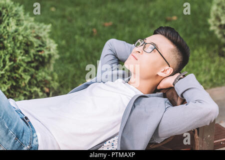 Schöne stilvolle asiatischer Mann träumen und Lügen auf der Werkbank Stockfoto