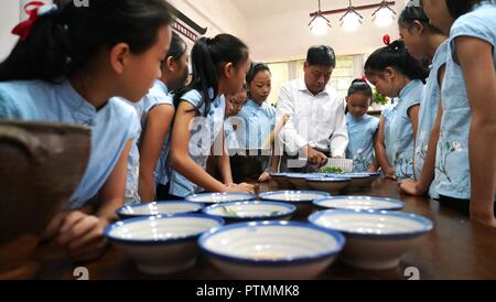 Nanchang, China's Jiangxi Province. 10 Okt, 2018. Liao Yongchuan, repräsentatives Erbe der Hakka Lei Cha, einem traditionellen Kaffee-basierte gruel, Technik, führt die zu Schüler quannan Nr. 4 Grundschule in Quannan County, der ostchinesischen Provinz Jiangxi, Okt. 10, 2018. Credit: Hu Chenhuan/Xinhua/Alamy leben Nachrichten Stockfoto