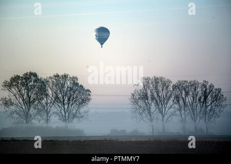 10 Oktober 2018, Nordrhein-Westfalen, Roggendorf: ein Heißluftballon-Pässe Bäume im Morgennebel. Foto: Federico Gambarini/dpa Stockfoto