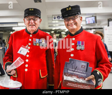 Victoria Station, London, 10. Okt 2018. Chelsea Rentner in ihren traditionellen scarlet Mäntel in der Victoria Station. Die Veteranen sammeln Spenden in zwölf Londoner U-Bahn-Stationen, heute im Namen der Nächstenliebe "erinnert". Eröffnungs-Projekt der Nächstenliebe", es aber nicht Es' hat das Ziel, zum Gedenken an jene, die in der WK 1 starb, die Jungen zu erziehen und die heutigen Veteranen leiden von der mentalen und körperlichen Wunden der Service während der Hundertjahrfeier 2018 heilen. Credit: Imageplotter Nachrichten und Sport/Alamy leben Nachrichten Stockfoto