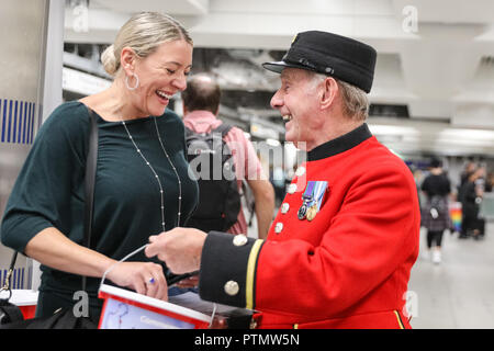 Victoria Station, London, 10. Okt 2018. Chelsea Rentner Tony, die erst 80, bezaubert die Menschen in Victoria Station. Die Veteranen sammeln Spenden in zwölf Londoner U-Bahn-Stationen, heute im Namen der Nächstenliebe "erinnert". Eröffnungs-Projekt der Nächstenliebe", es aber nicht Es' hat das Ziel, zum Gedenken an jene, die in der WK 1 starb, die Jungen zu erziehen und die heutigen Veteranen leiden von der mentalen und körperlichen Wunden der Service während der Hundertjahrfeier 2018 heilen. Credit: Imageplotter Nachrichten und Sport/Alamy leben Nachrichten Stockfoto