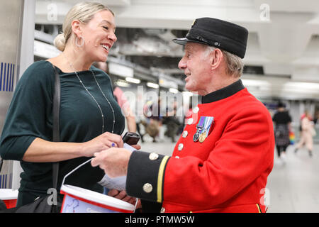 Victoria Station, London, 10. Okt 2018. Chelsea Rentner Tony, die erst 80, bezaubert die Menschen in Victoria Station. Die Veteranen sammeln Spenden in zwölf Londoner U-Bahn-Stationen, heute im Namen der Nächstenliebe "erinnert". Eröffnungs-Projekt der Nächstenliebe", es aber nicht Es' hat das Ziel, zum Gedenken an jene, die in der WK 1 starb, die Jungen zu erziehen und die heutigen Veteranen leiden von der mentalen und körperlichen Wunden der Service während der Hundertjahrfeier 2018 heilen. Credit: Imageplotter Nachrichten und Sport/Alamy leben Nachrichten Stockfoto