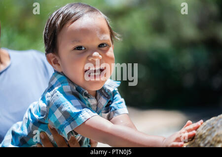 Jungen Sohn Kleinkind erreichen, berühren, spielen und genießen Sie den Sommer mit Mutter im Freien in einem Park, enthusiastisch und Lachen Stockfoto