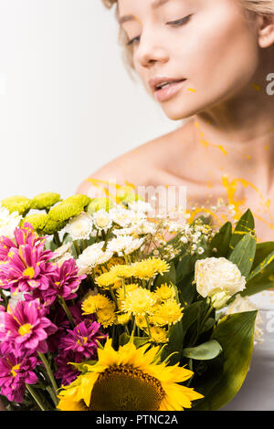 Attraktive Frau mit Blumenstrauß und gelbe Farbe auf Körper isoliert auf weiss Stockfoto