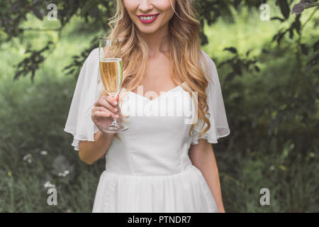 7/8 Schuß von lächelnden jungen blonden Braut holding Glas Wein im Freien Stockfoto