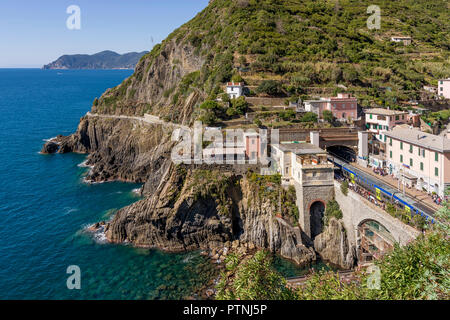 Zug in den Bahnhof Riomaggiore mit 'La Via dell'Amore' im Hintergrund, Cinque Terre, Ligurien, Italien Stockfoto