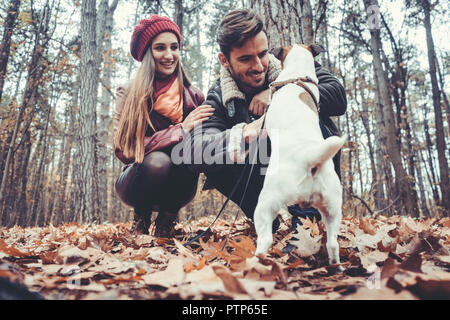 Paar von Frau und Mann spielt mit ihrem Hund in den bunten Herbst Landschaften Stockfoto