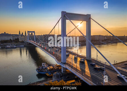 Budapest, Ungarn - schöne Elisabeth Brücke (Erzsebet Hid) bei Sonnenaufgang mit goldenen und blauen Himmel, schwere Morgen Verkehr und traditionellen gelben Straßenbahn ein Stockfoto