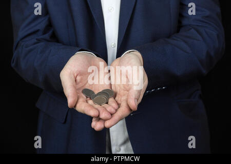 Ein Mann in einer Jacke hält Münzen auf den Armen seiner Hände Stockfoto