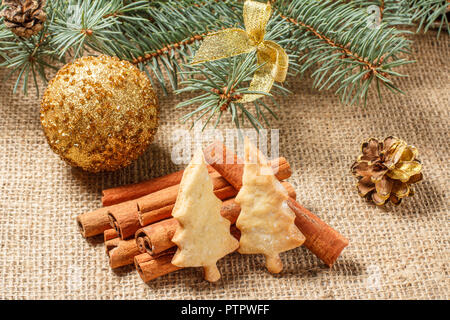 Gingerbread Cookies in Weihnachtsbaum Form auf einen Sack mit Zimt, Sternanis, rauschende Ballnacht und natürliche Tanne Zweige mit Zapfen Stockfoto