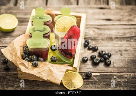 Hausgemachtes Eis in den Formen liegt in einer schönen Holzkiste auf hölzernen Hintergrund, Konzept, kühlen Speisen und Eis Stockfoto