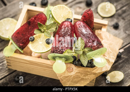 Hausgemachtes Eis in den Formen liegt in einer schönen Holzkiste auf hölzernen Hintergrund, Konzept, kühlen Speisen und Eis Stockfoto