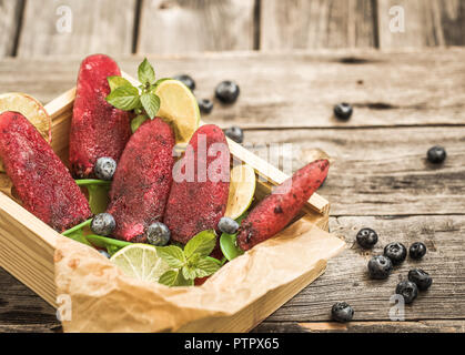 Hausgemachtes Eis in den Formen liegt in einer schönen Holzkiste auf hölzernen Hintergrund, Konzept, kühlen Speisen und Eis Stockfoto