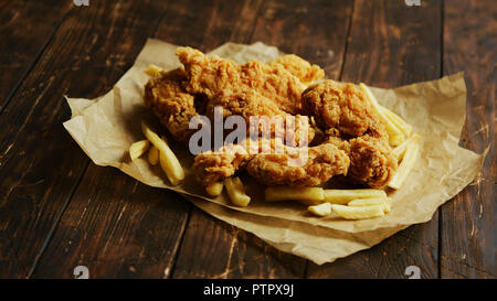 Pommes frites und Chicken Wings auf Pergament Stockfoto