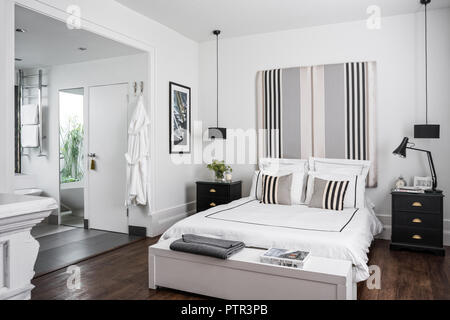Doppelbett mit Kopfteil in Ariana Parini Stoff aus dem Designers Guild bedeckt mit Bettwäsche von White Company Stockfoto