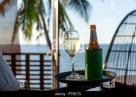 Kellner seaving Glas Weisswein und eine Flasche Bier auf ein Fach am Strand Stockfoto