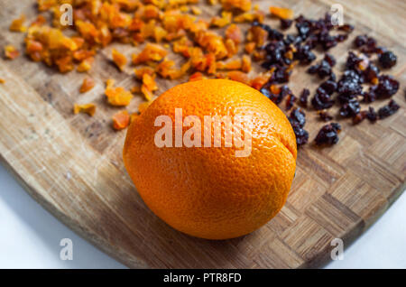 Orange, gehackte getrocknete Aprikosen und Pflaumen auf einer hölzernen Schneidebrett. Gesunde Ernährung Food Ingredients. Stockfoto