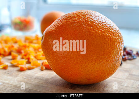 Orangen, gehackte getrocknete Aprikosen und Pflaumen auf einer hölzernen Schneidebrett. Gesunde Ernährung Food Ingredients. Stockfoto