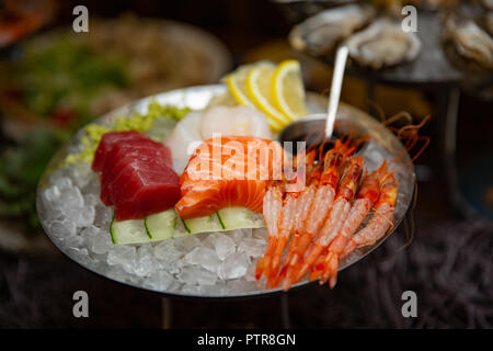 Gemischte sashimi Fisch in Scheiben geschnitten auf Eis im schwarzen Schüssel. Sashimi Lachs Thunfisch Hamachi Garnelen und Surf Ruhig, roher Fisch, Garnelen japanisches Essen in asiatischen Wäs Stockfoto