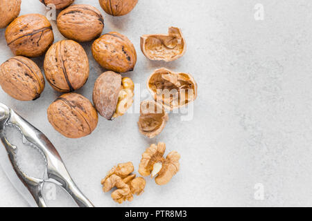 Ganzen und gebrochenen Walnüsse neben Silber Nussknacker auf weißem Hintergrund Stockfoto