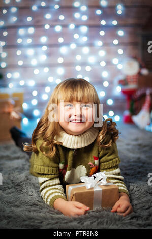 Schöne süße kleine Mädchen auf Weihnachten Hintergrund mit Geschenk Stockfoto