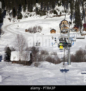 Skifahrer auf der Sesselbahn am Ski Resort in Sun winter Tag. Kaukasus Berge. Hatsvali, Swaneti Region Georgiens. Quadratisches Bild. Stockfoto