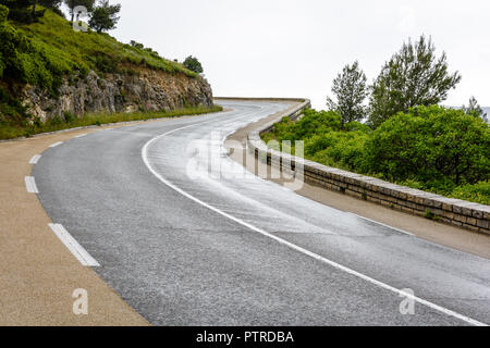 Nasse Mountain Road mit steinernen Brüstung wicklung Berghang im Süden von Frankreich an einem regnerischen Tag. Stockfoto