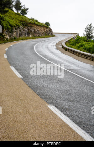 Nasse Mountain Road mit steinernen Brüstung wicklung Berghang im Süden von Frankreich an einem regnerischen Tag. Stockfoto