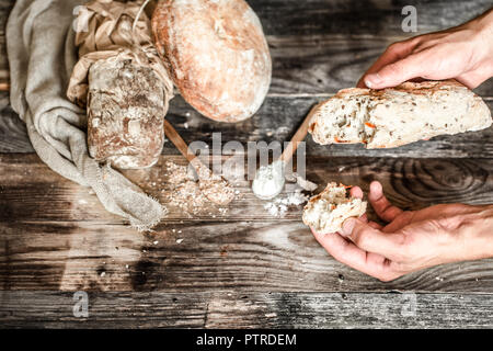 Die Zubereitung von Brot, frische und köstliche Brot und Hände mit Mehl auf die alten hölzernen Hintergrund, Konzept zum Backen Stockfoto