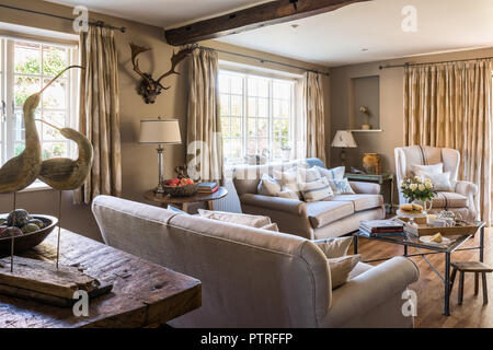 Neutrale Sofas mit Wand Geweih und Vogel Ornamente in restaurierten Bauernhaus aus dem 16. Jahrhundert montiert Stockfoto