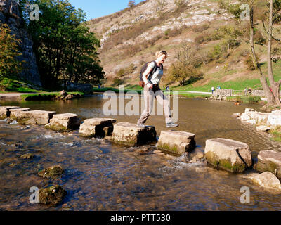 Nationalpark Peak District, Derbyshire, UK. 10. Oktober, 2018. UK Wetter Frau Kreuzung die Trittsteine auf einem ungewöhnlich heißen sonnigen Oktobertag im touristischen Hotspot von Dovedale im Peak District National Park, Derbyshire Credit: Doug Blane/Alamy leben Nachrichten Stockfoto