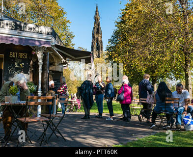 Die Princes Street Gardens, Edinburgh, Schottland, Großbritannien, 10. Oktober 2018. UK Wetter: die Menschen in den warmen Sonnenschein unter den Herbst Baum Farben und Warteschlange sitzen, zu Eis aus einem Lebensmittel kaufen Abschaltdruck Stockfoto