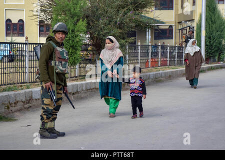 Oktober 10, 2018 - Baramulla, Jammu und Kaschmir, Indien - Eine Armee Mann gesehen stehen auf der Hut wie eine Frau, die Wanderungen von einem Wahllokal während der Wahlen.. Zweite Phase der städtischen lokalen Körper (ULB) Wahlen in Jammu und Kaschmir. Sommer Hauptstadt des Indischen kontrollierten Kashmir, Srinagar. Dieser hatte den niedrigsten Umsatz der Wähler bei den Kommunalwahlen. (Bild: © idrees Abbas/SOPA Bilder über ZUMA Draht) Stockfoto