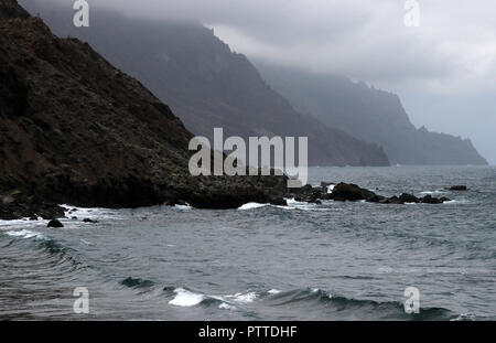 Wild zerbröckelt Abschnitt der Klippe an der Playa del Roque de las Bodegas in der Nähe von Taganana im Norden der Kanarischen Insel Teneriffa auf 24.09.2018. Niedrige Wolken, unberechenbaren Wellen mit starken Strömungen - hier relativ ungestört Baden, aber auf eigene Gefahr. | Verwendung weltweit Stockfoto