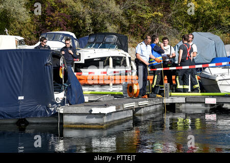 11 Oktober 2018, Baden-Wuerttemberg, Kressbronn: Polizisten und Feuerwehrleute stehen an der Unfallstelle, wo mehrere Motoryachten verbrannt haben. Foto: Felix Kästle/dpa Stockfoto