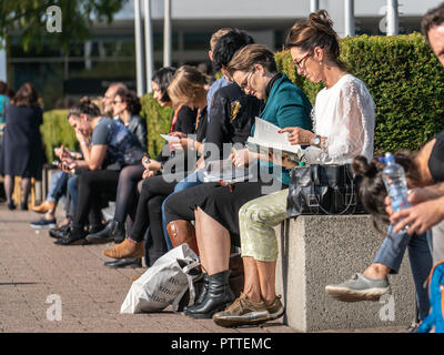 11 Oktober 2018, Hessen, Frankfurt Main: Besucher der Buchmesse sitzen in der Sonne auf der Agora des Messegeländes. Größte Buch der Welt zeigen, dauert bis zum 14. Oktober 1999 statt. Foto: Frank Rumpenhorst/dpa Stockfoto