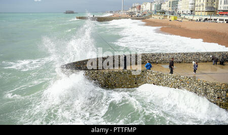 Brighton UK 11. Oktober 2018 - ein Fischer und Besucher fast Catch eine große Welle in Absturz auf Brighton Seafront wie Stürme mit starken Winden Prognose sind einige Teile Großbritanniens zu schlagen morgen: Simon Dack/Alamy leben Nachrichten Stockfoto