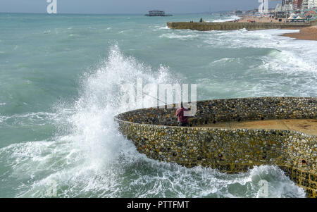 Brighton UK 11. Oktober 2018 - ein Fischer fast Fänge eine große Welle in Absturz auf Brighton Seafront wie Stürme mit starken Winden Prognose sind einige Teile Großbritanniens zu schlagen morgen: Simon Dack/Alamy leben Nachrichten Stockfoto